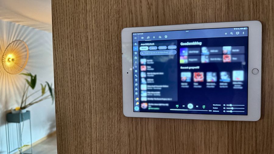 Tablet aan een houten wand in de woonkamer, met het muziekscherm open