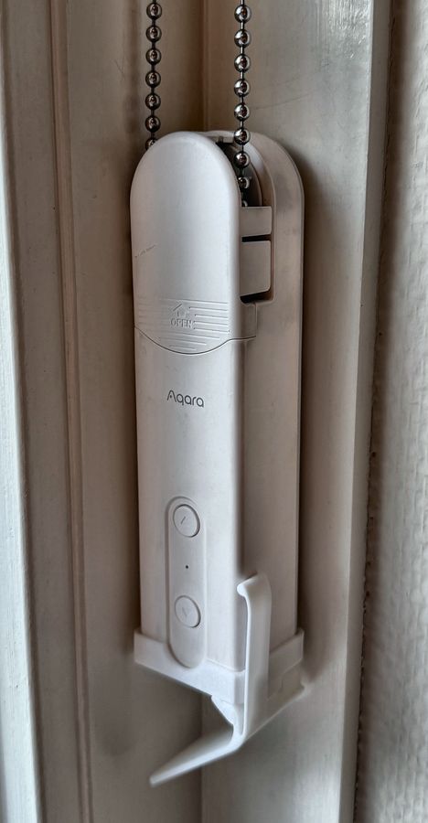 Close-up van het witte motortje aan het kettinkje van het rolgordijn