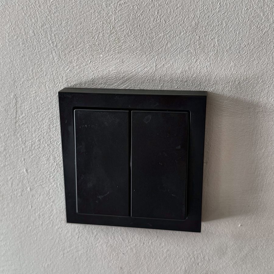 Een zwarte dubbele wandschakelaar op een lichte muur