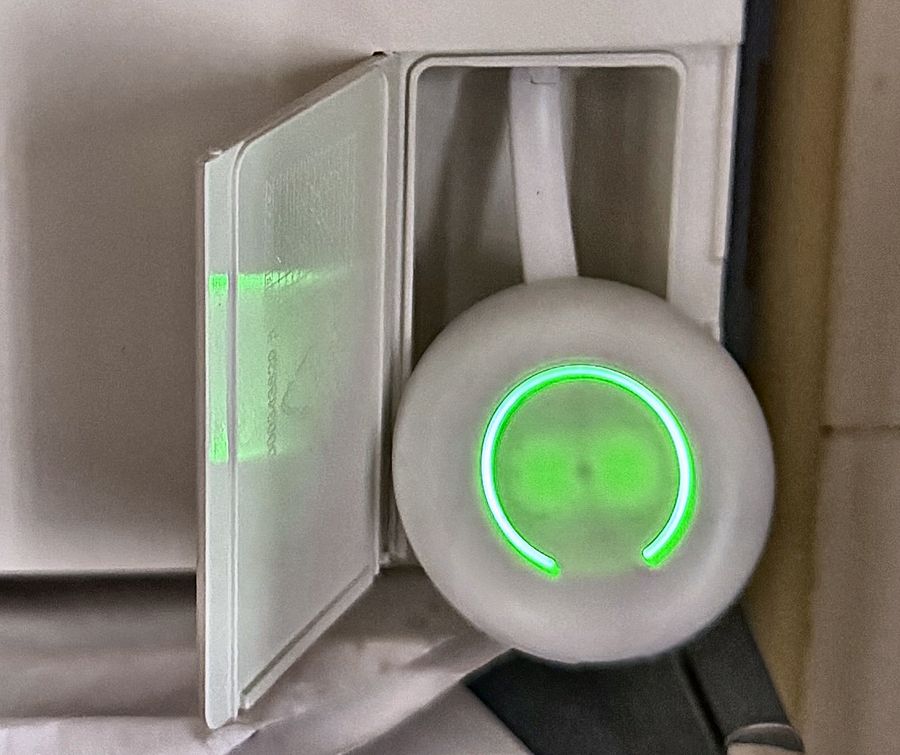 Een ronde uitlezer met een groen lampje op de slimme meter in de meterkast