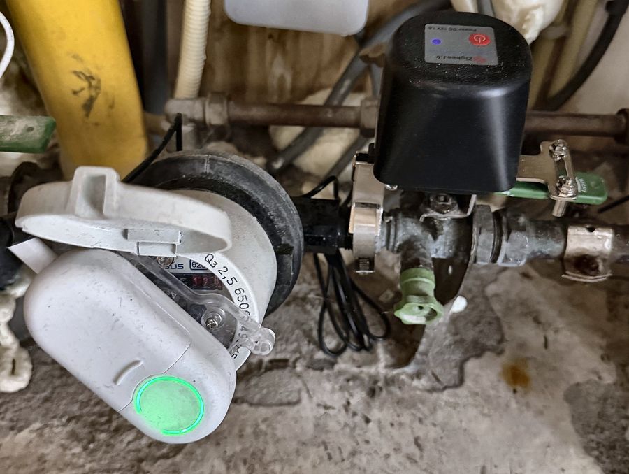 In de meterkast: een uitlezer op de watermeter en een zwarte motor op de waterleiding